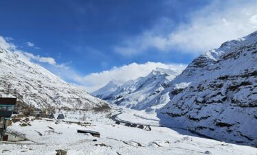 Vast snow-covered plain area in Sissu village surrounded by Himalayan peaks and clear blue sky