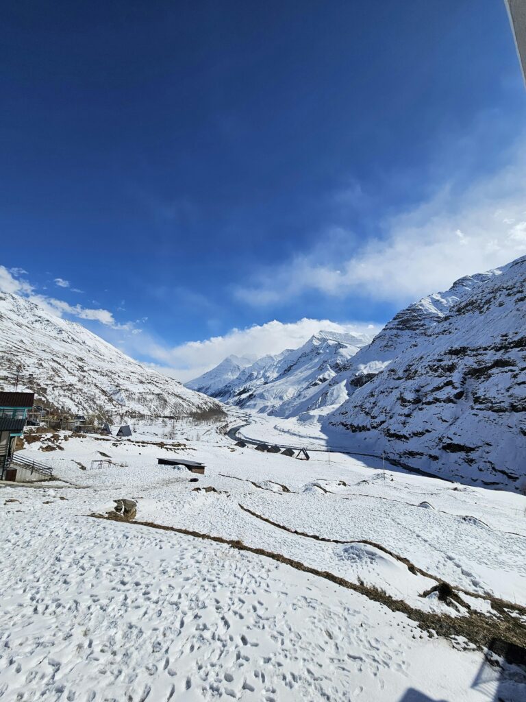 Vast snow-covered plain area in Sissu village surrounded by Himalayan peaks and clear blue sky